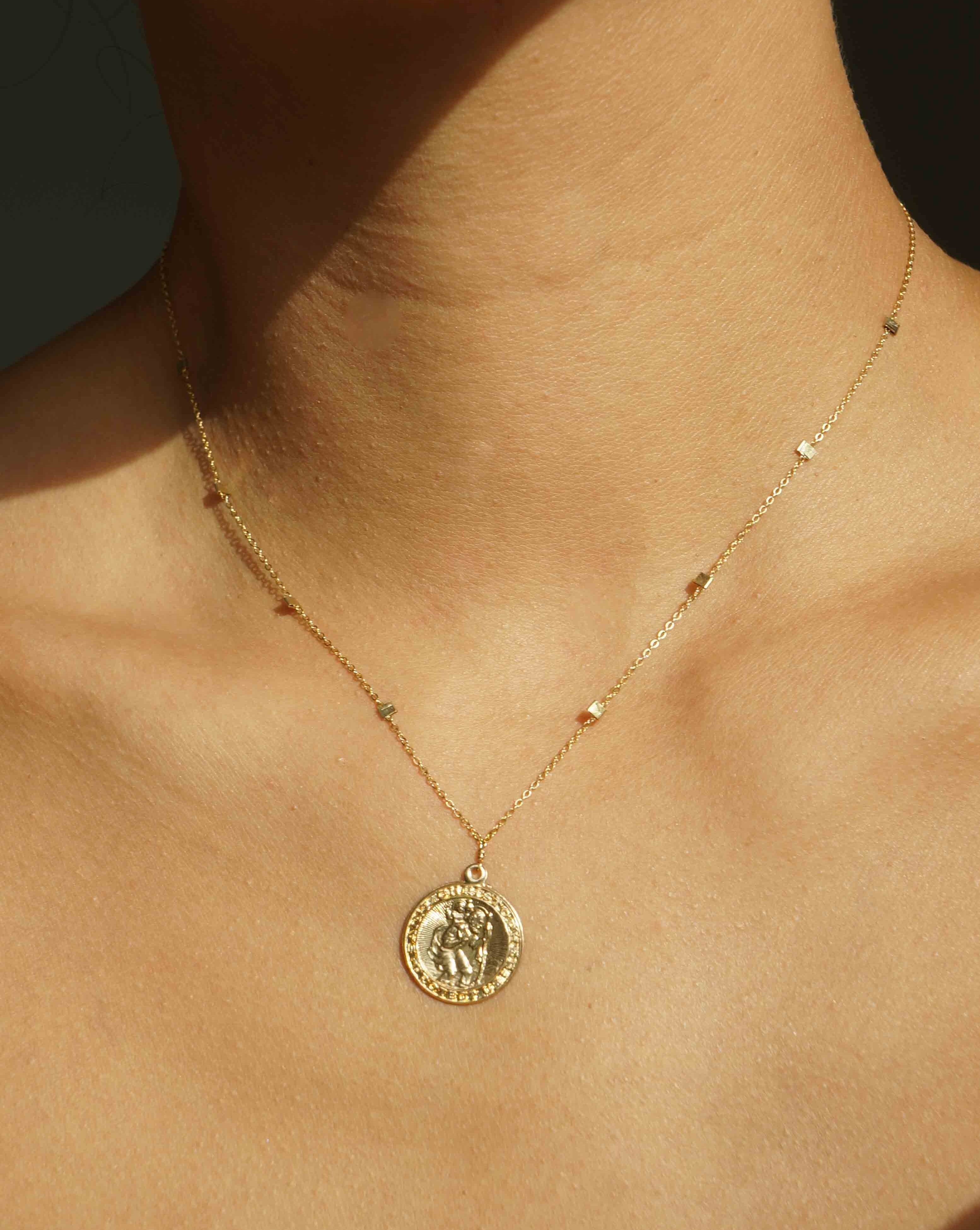 San Cris Necklace by KOZAKH. A 16 to 18 inch adjustable length necklace, crafted in 14K Gold Filled, featuring a 16mm Saint Christopher Medallion.