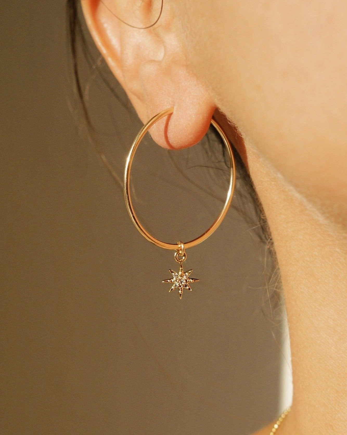 Soleil Hoop Earrings by KOZAKH. 30mm hoop earrings, crafted in 14K Gold Filled, featuring a dangling Cubic Zirconia 6 point star charm.
