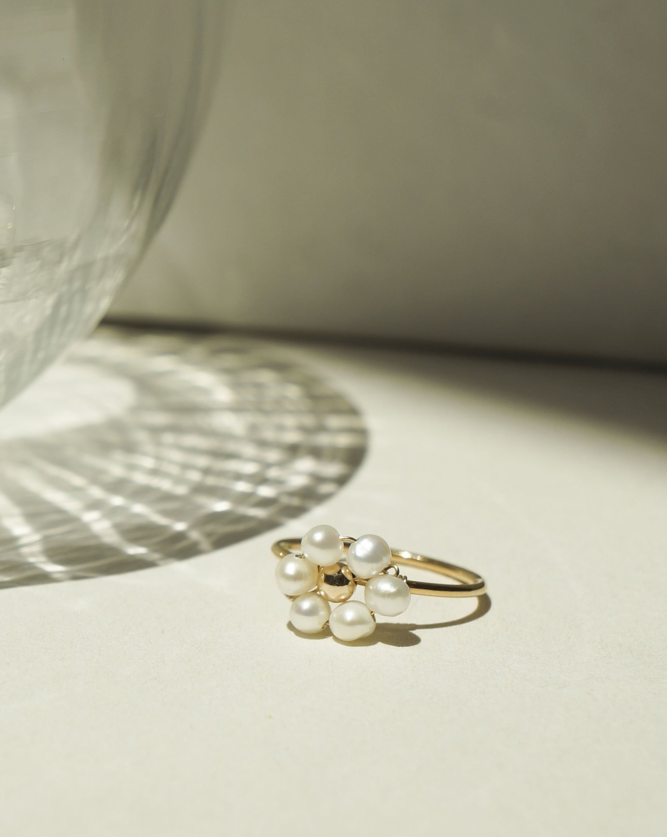 Sun Ring by KOZAKH. A 1mm round ring, crafted in 14K Gold Filled, featuring white freshwater Pearls and a gold bead forming a handmade daisy charm.