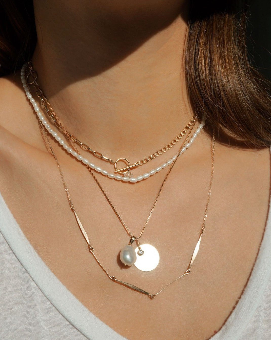 Sylet Necklace by KOZAKH. A 16 to 18 inch adjustable length necklace, crafted in 14K Gold Filled, featuring a 9mm Oval pearl, a 16mm Coin medallion, and a 3mm Cubic Zirconia bezel.