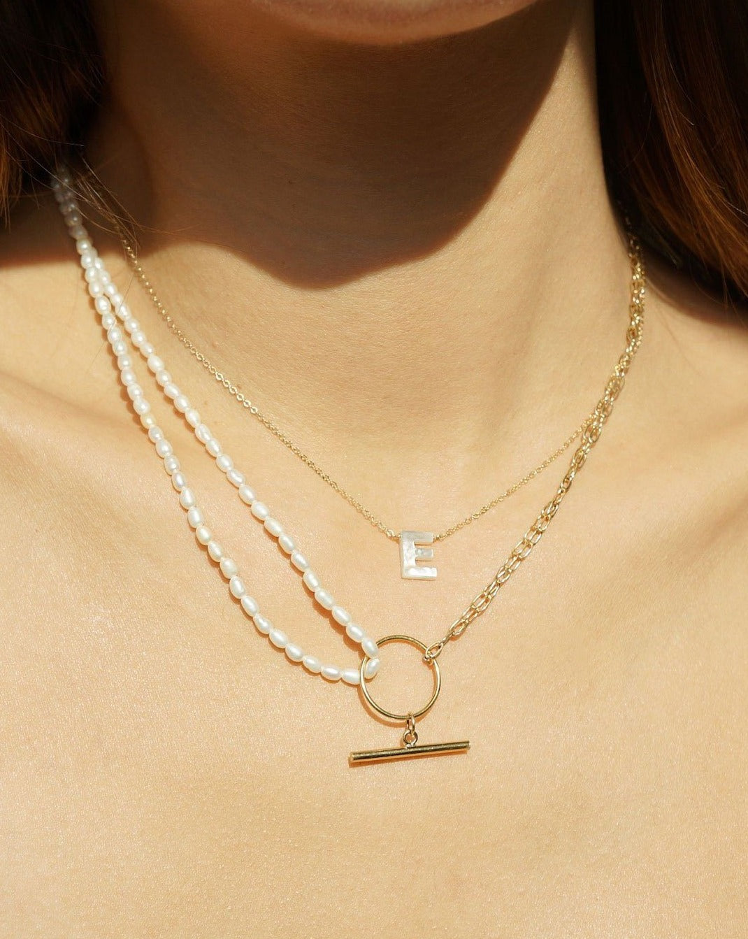 Trillian Necklace by KOZAKH. A 16 to 18 inch adjustable length necklace, with 4mm white pearl strand on one half, the other half is crafted in 14K Gold Filled, featuring a horizontal bar.