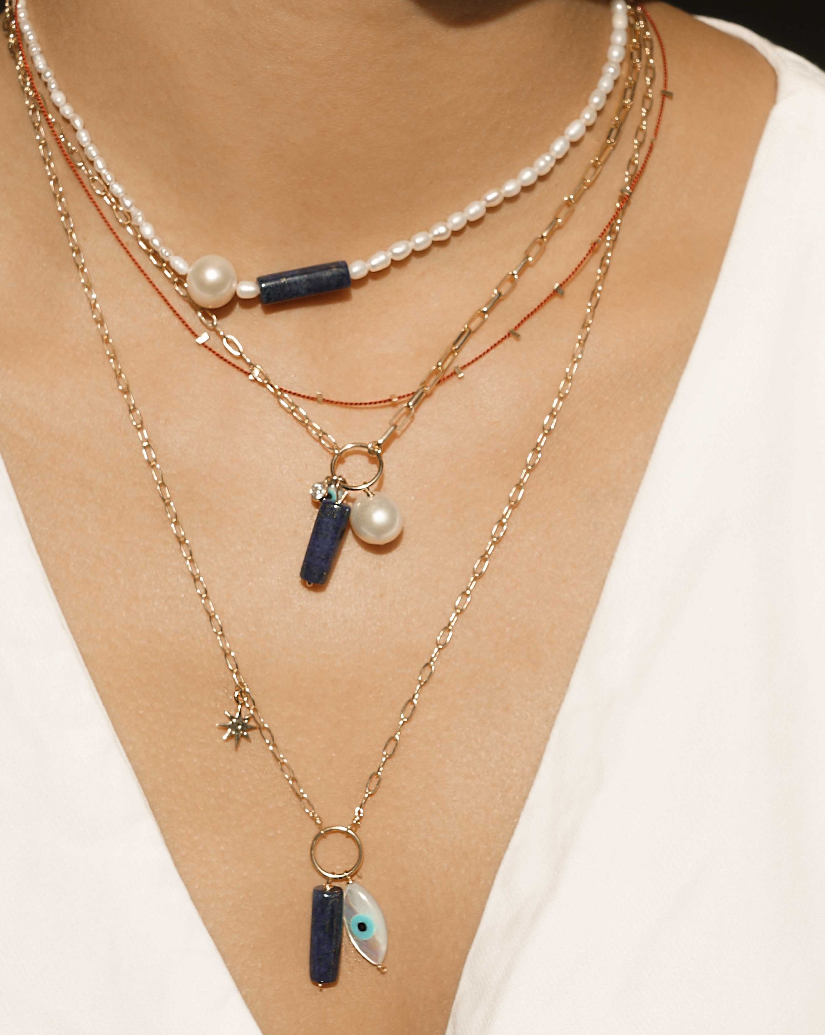 Wisdomkeeper Necklace by KOZAKH. A 15 to 17 inch adjustable length, freshwater rice pearl strand necklace, clasp crafted in 14K Gold Filled, featuring a round Freshwater Pearl and a cylindrical cut Lapis. 