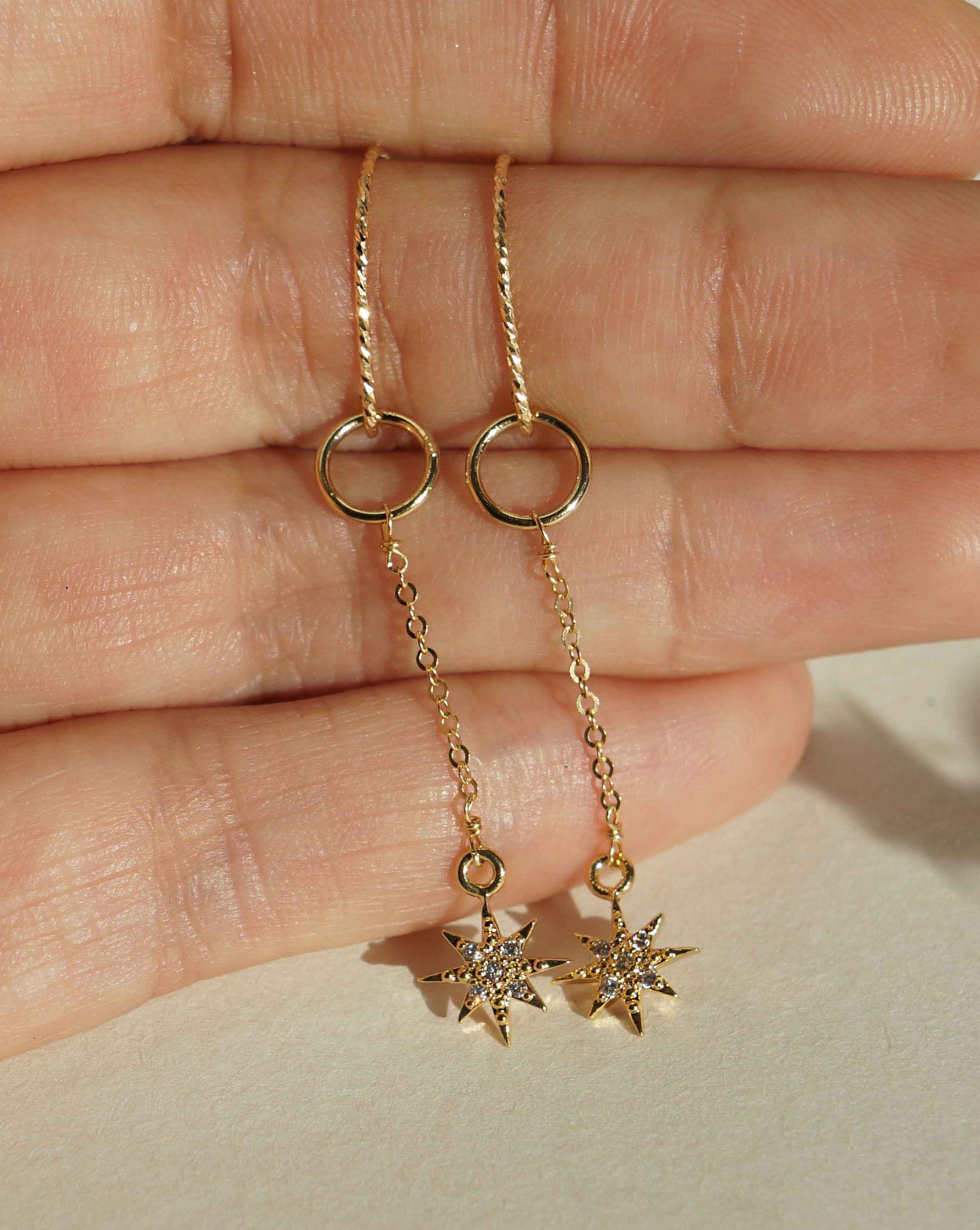 You Stardrop Earrings by KOZAKH. Diamond textured hook dangling earrings, crafted in 14K Gold Filled, featuring a Cubic Zirconia encrusted 8 point star charm.